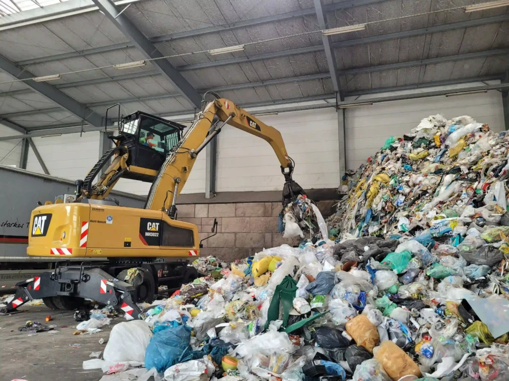 ゴミ処理施設で大量のプラスチックごみを移動させるCAT製MH3022重機